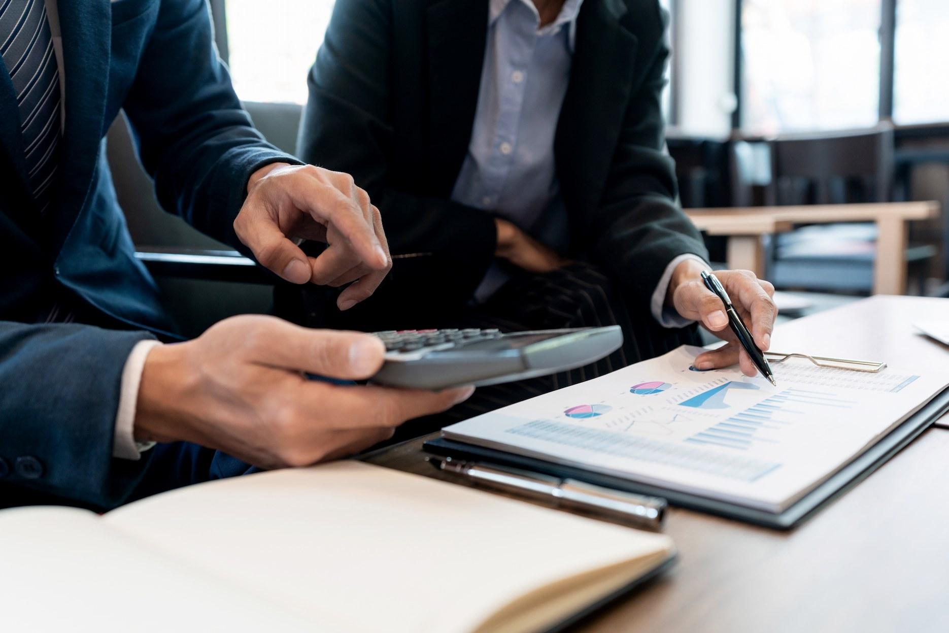 Business consultants reviewing financial documents and calculating the cost of setting up a business in Dubai.