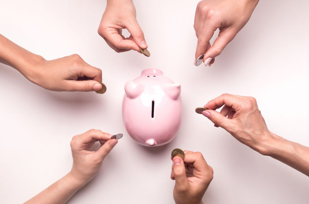 Hands Putting Money Into Piggy Bank