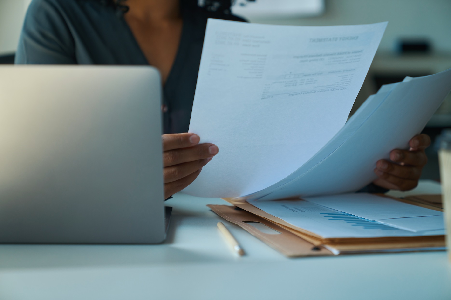 Professional reviewing company tax and financial documents beside a laptop.