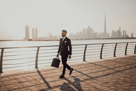 A stock photo of a businessman with briefcase along the water in Dubai.