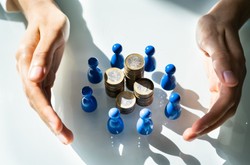 Hands, Coins And Models On White Desk.