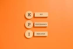 Orange back ground with wooden tiles spelling out KPI which is a vital part of a sales strategy