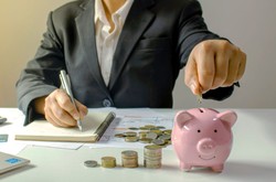 Businessman Putting Money Into Piggy Bank