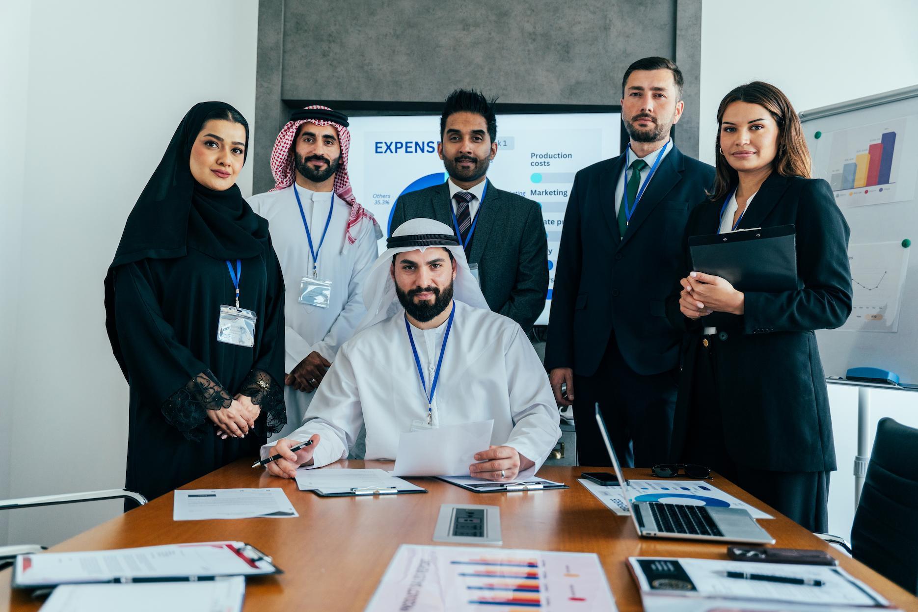 Business team with Emirati professionals reviewing company expenses in a modern office.